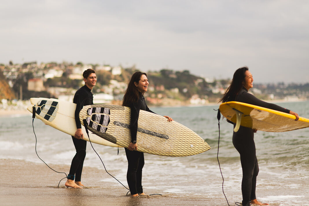 Three friends standing on beach before surfing